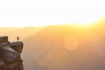 person on cliff with sunlandscape pandemic reflection